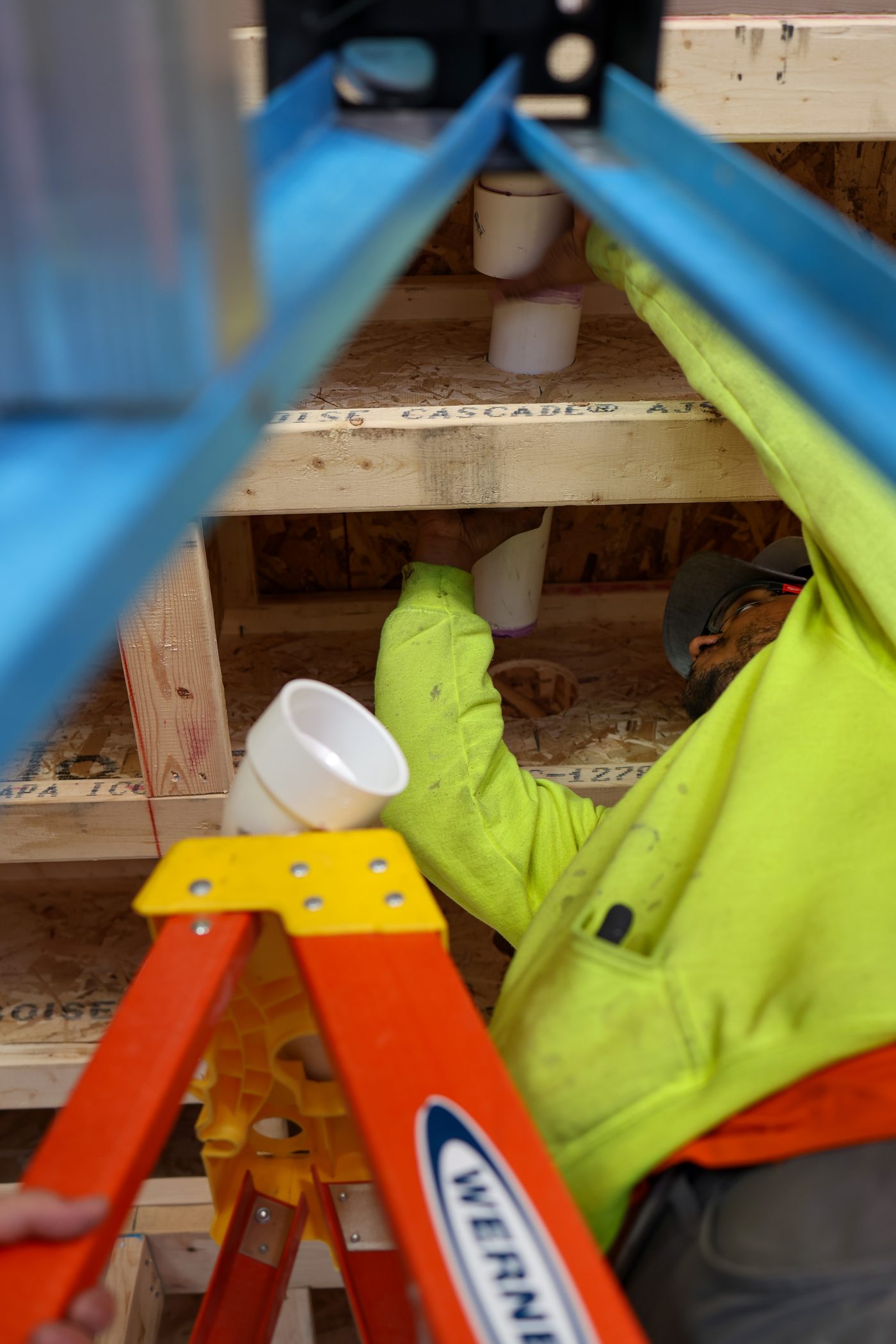 A Hertel plumber fitting PVC drainage between floor joists