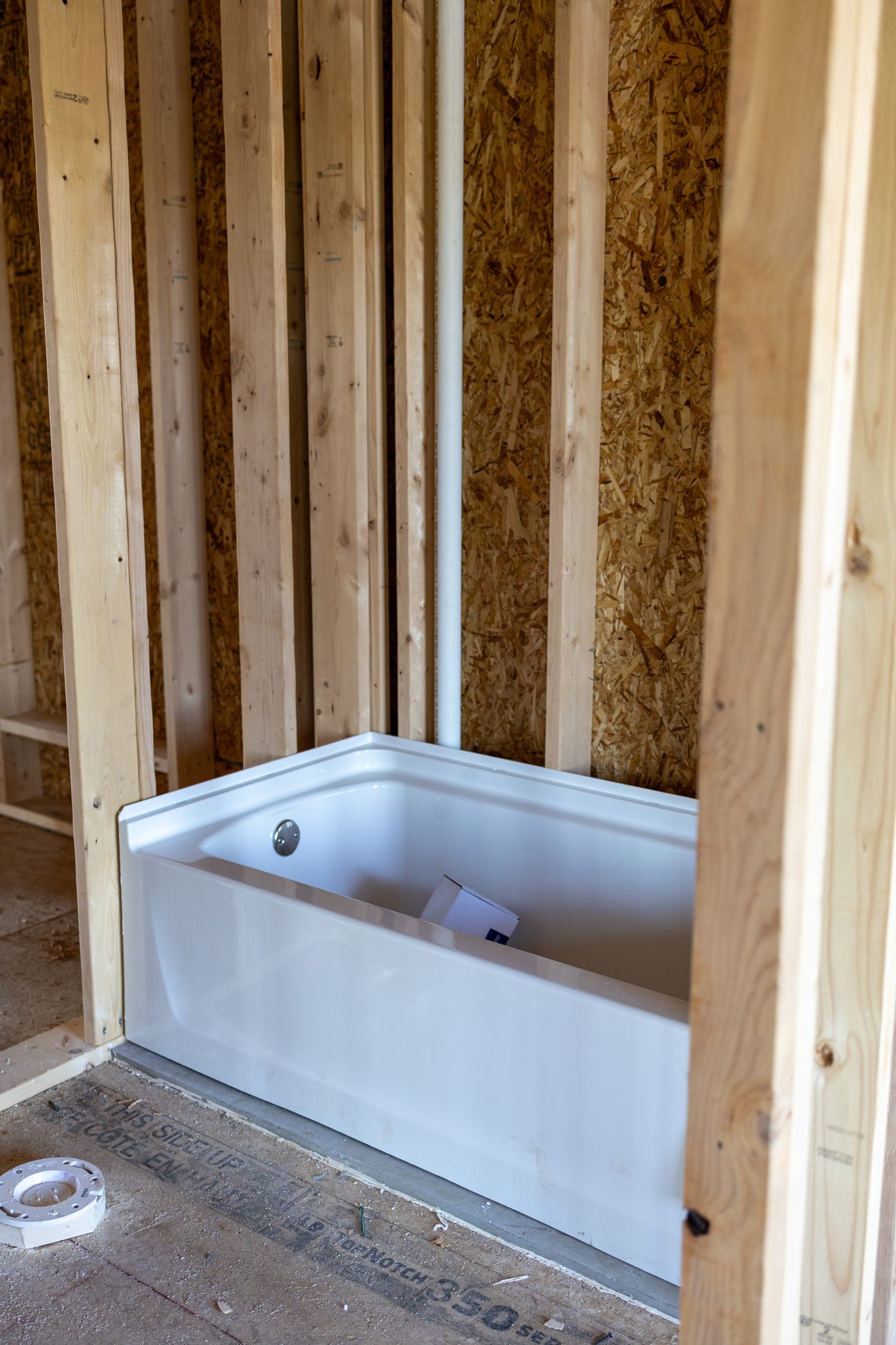 A tub set into stud framing at rough-in stage