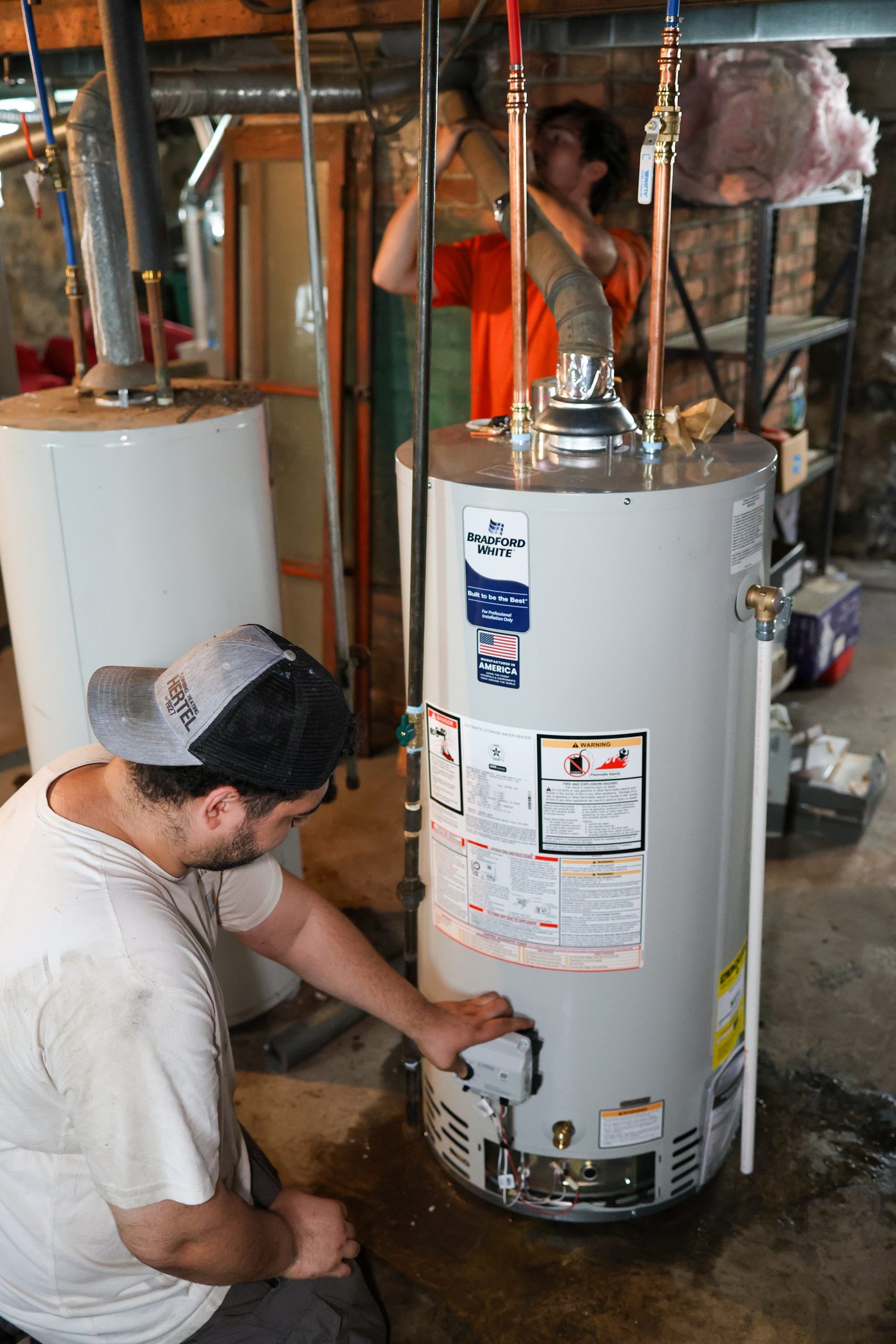 A Hertel plumber connecting a new Bradford White water heater