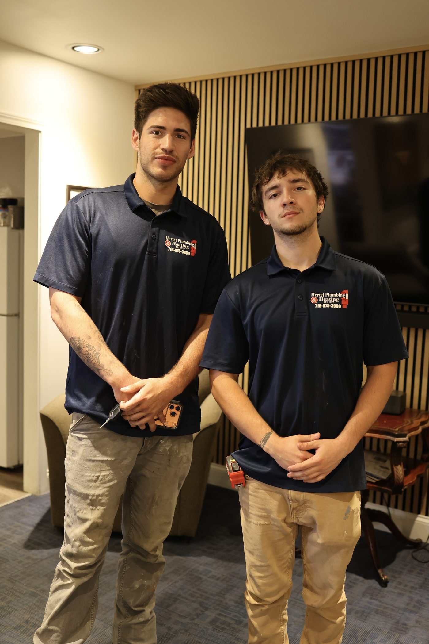 Two Hertel plumbers in branded polo shirts on a service call