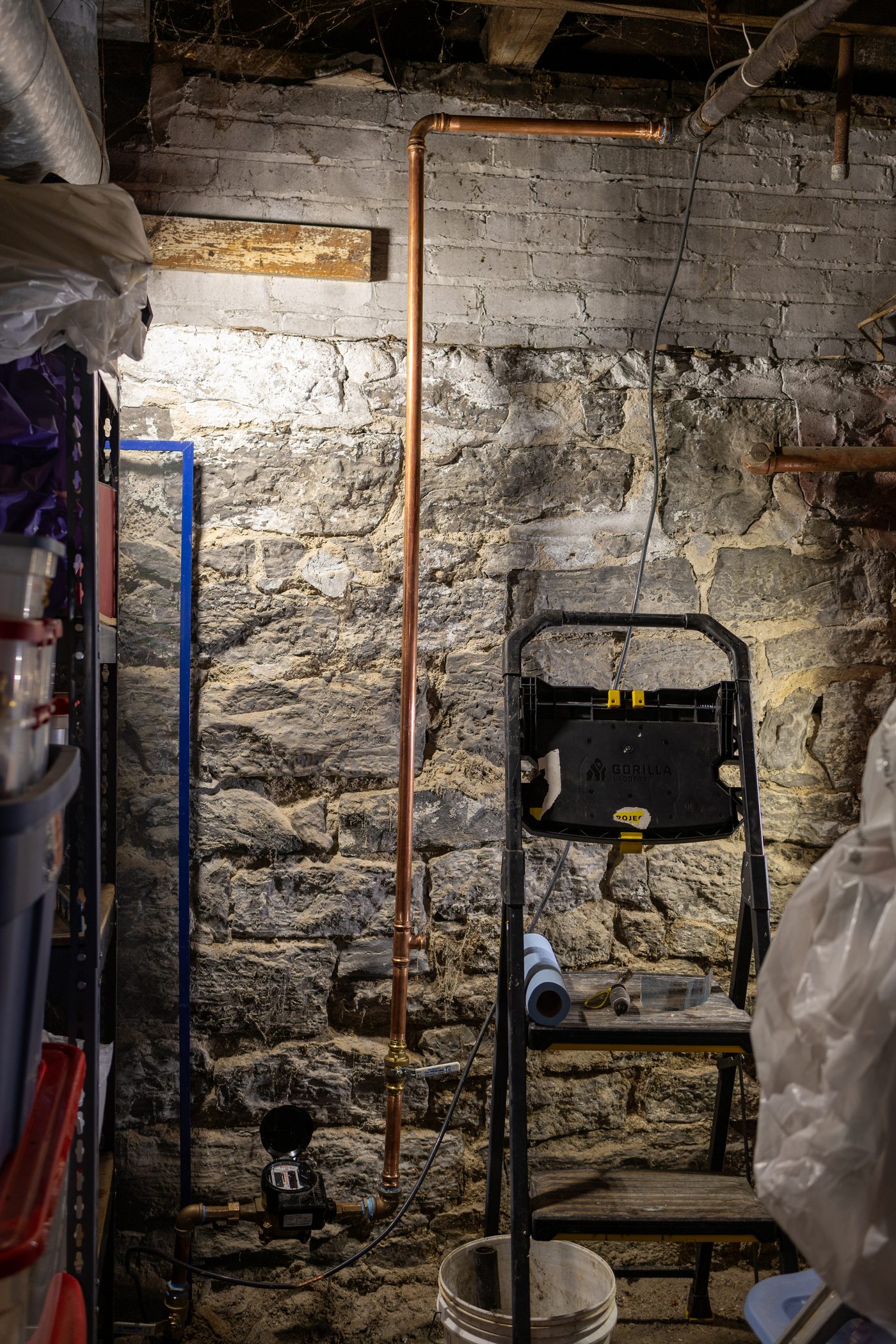 A new copper water service riser and meter against an old stone foundation wall
