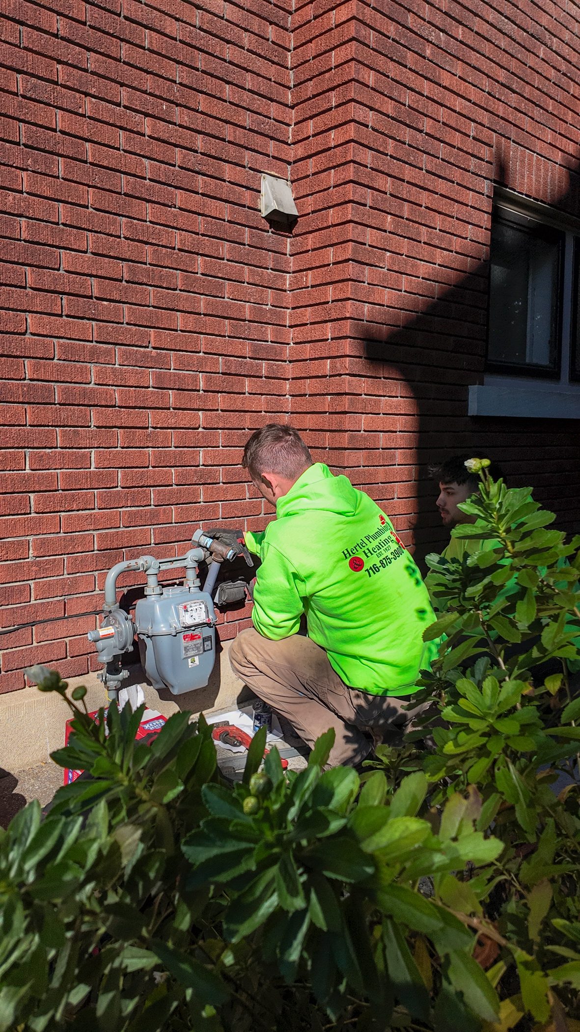 A Hertel plumber working on an exterior gas meter and regulator