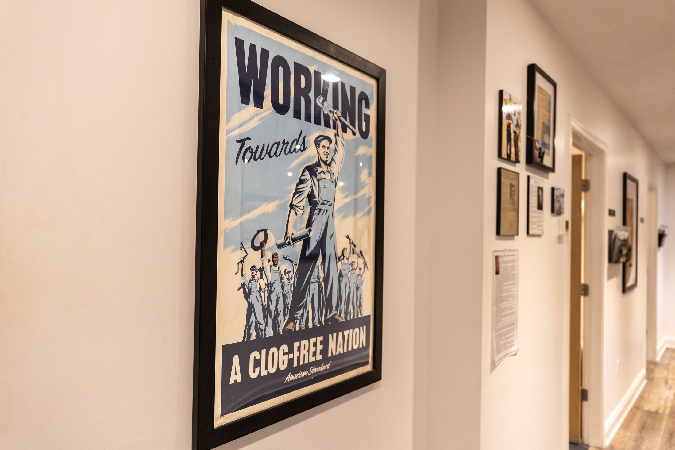 A framed vintage American Standard plumbing poster on the office wall at Ramsdell Avenue